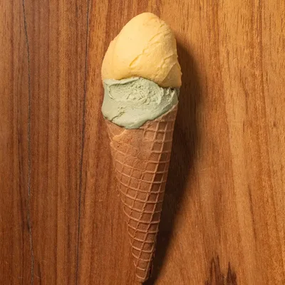 Casquinha com duas bolas de gelato apoiada na mesa de madeira